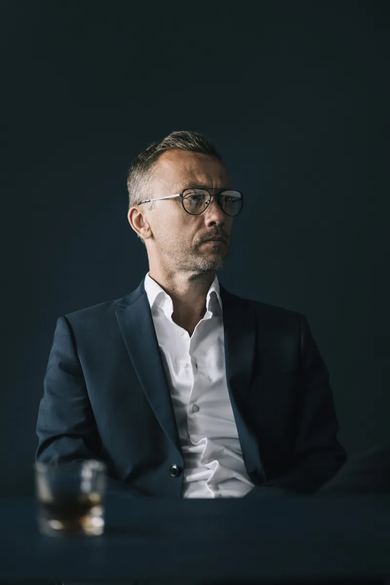 Meelis Vill ülikonnas stuudiovalguses seismas